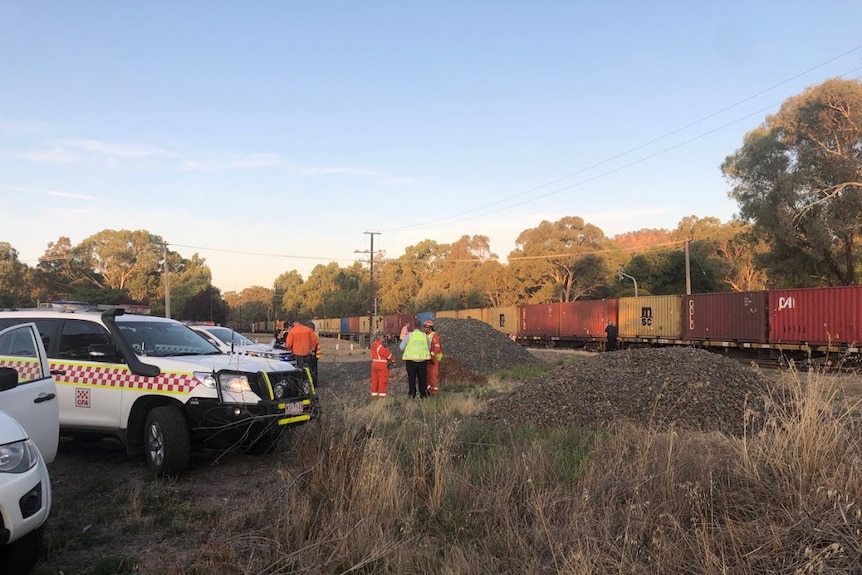 Carriages from a V-Line train and a freight train sit askew off the rails.