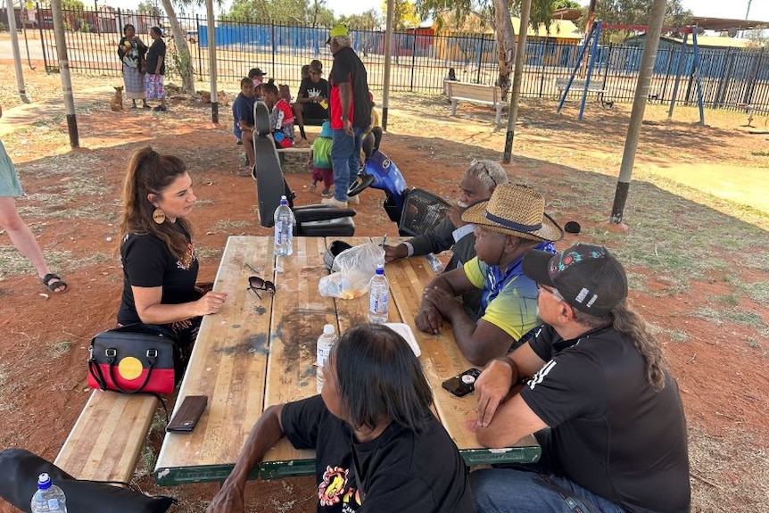 People gather round a park table in the remote community of community