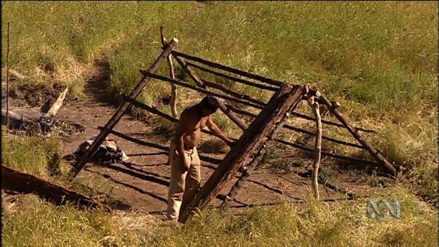 Man stands beside large wooden roof frame