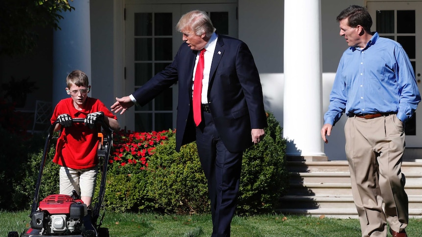 Frank Giaccio, 11, (left) is accompanied by President Donald Trump as he mows the lawn of the Rose Garden