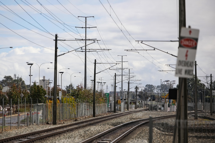A section of train line with powerlines overhead.