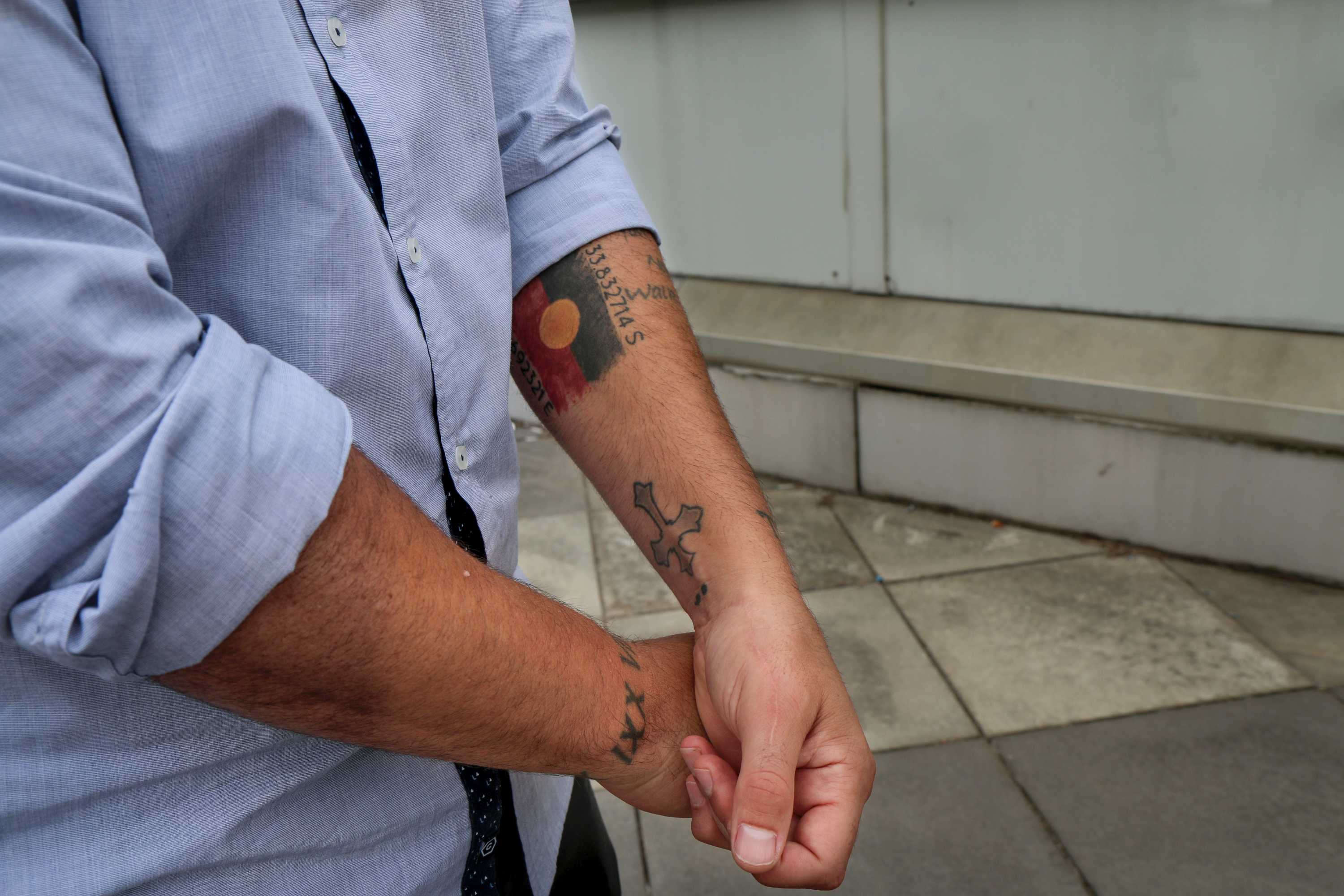 Tattoos on the arms of Joe Williams, including the Aboriginal flag up his forearm.