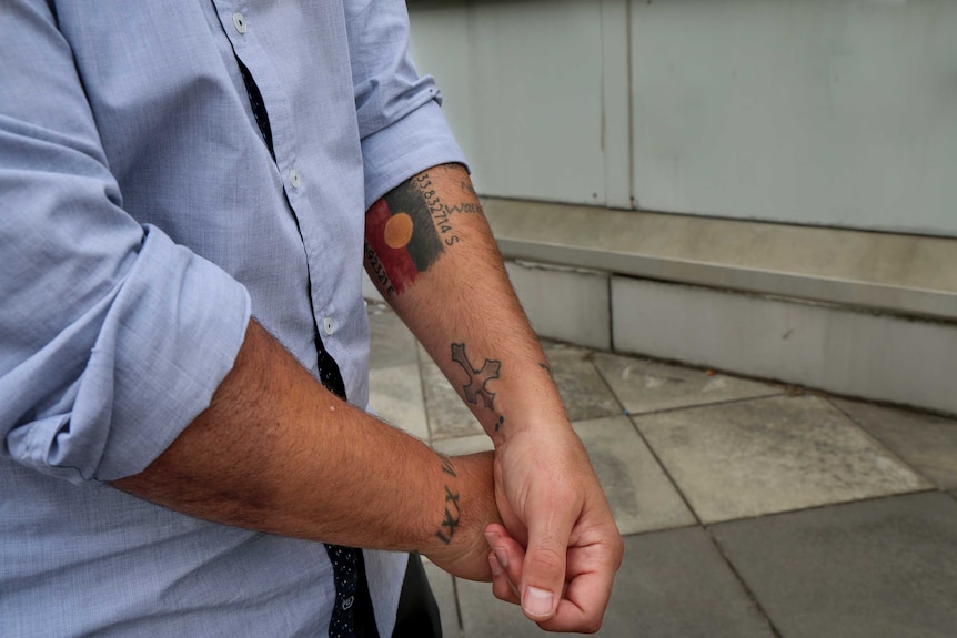 Tattoos on the arms of Joe Williams, including the Aboriginal flag up his forearm.
