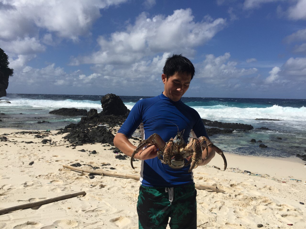 Daniel at the beach holding a large crustacean.