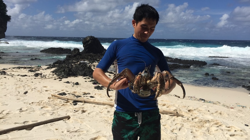 Daniel at the beach holding a large crustacean.