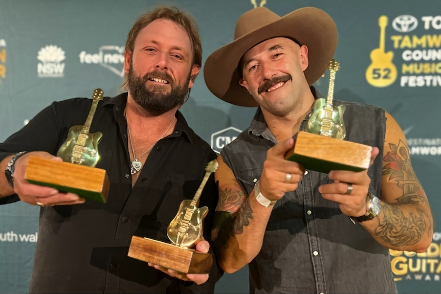 Two men holding Golden Guitar awards