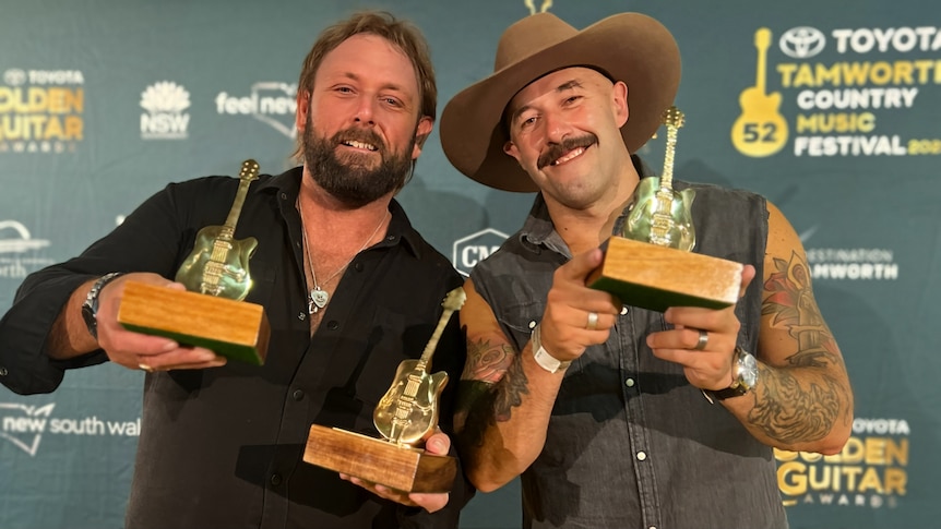 Two men holding Golden Guitar awards