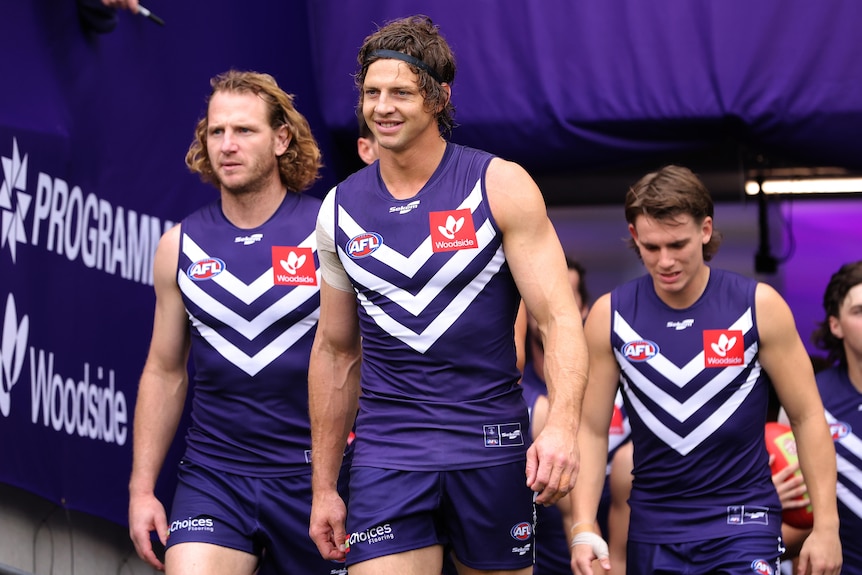Nat Fyfe entering the field surrounded by teammates 