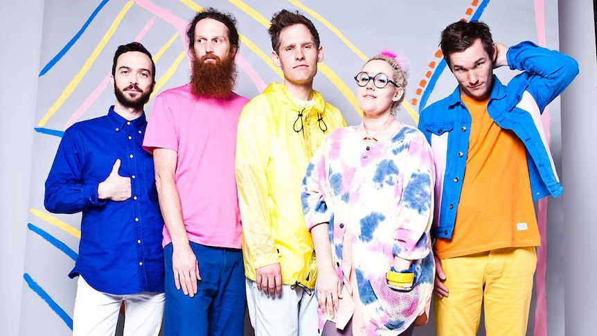 Architecture In Helsinki wear pastel coloured clothes and stand in front of a colourful painting