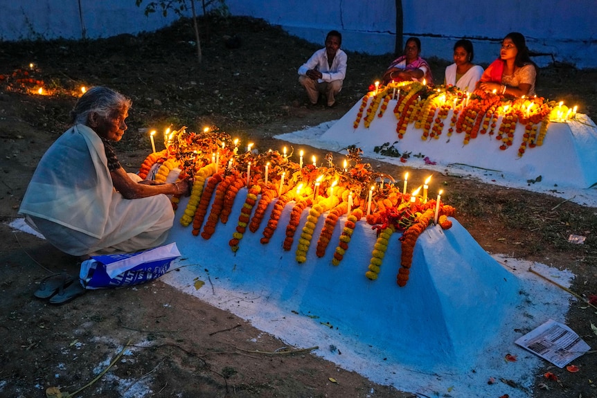 Indian Christian families wear white clothes as they light candles and put flowers on the raised graves of family.