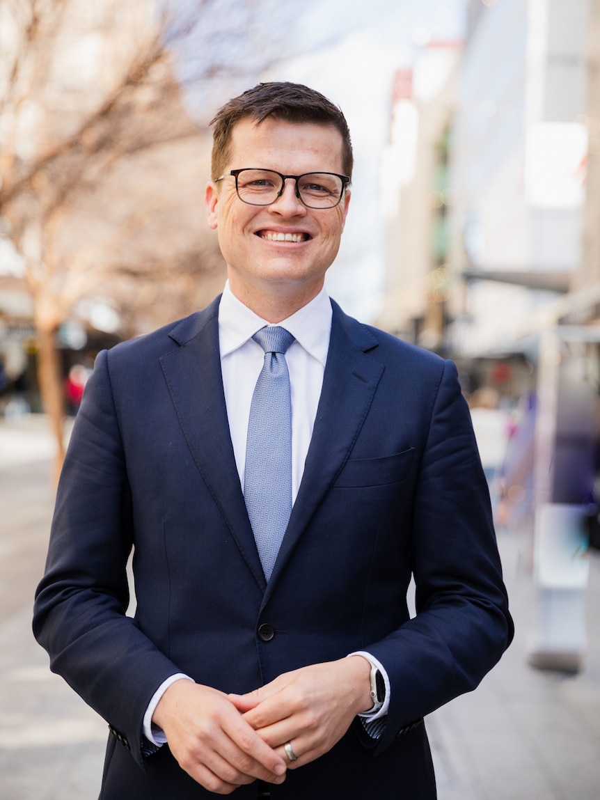 a professional man with glasses and a suit in a city setting