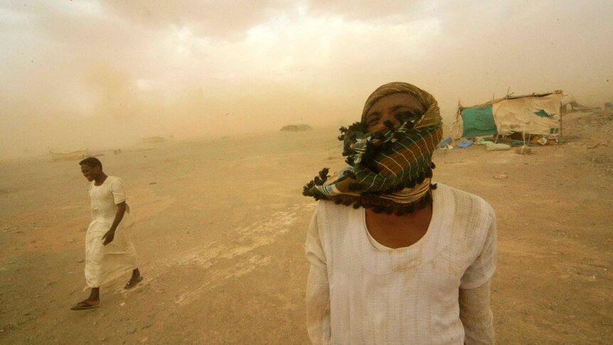 Sudan gold mine workers walk through a sand storm
