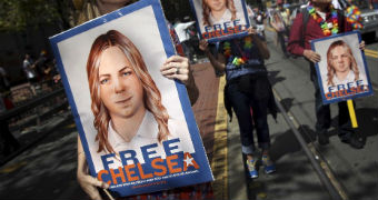 Women walk down the street holding Free Chelsea placards