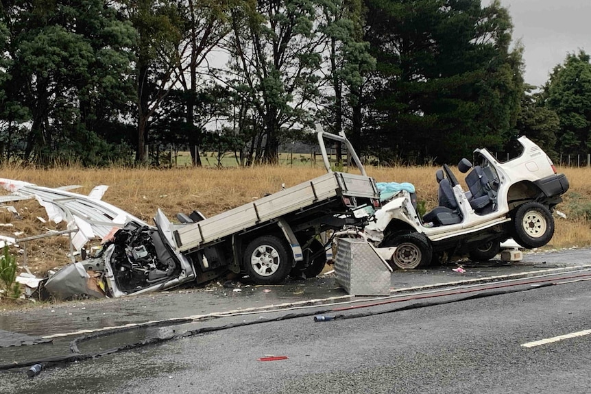 Two heavily damaged cars - a ute and a four-wheel drive - are crashed off the side of a highway