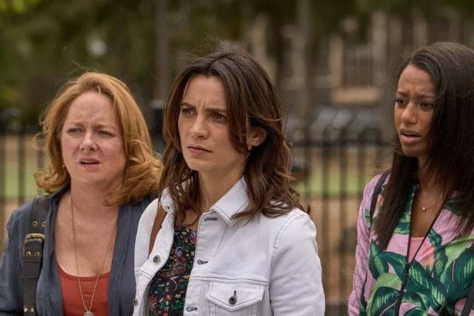 Three women outside a school looking concerned
