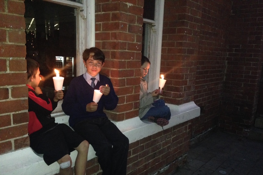 Schoolchildren hold candles at a Light the Dark vigil in Perth