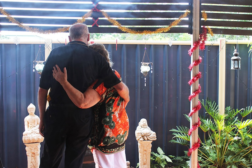 Two parents staring at a memorial to their dead son