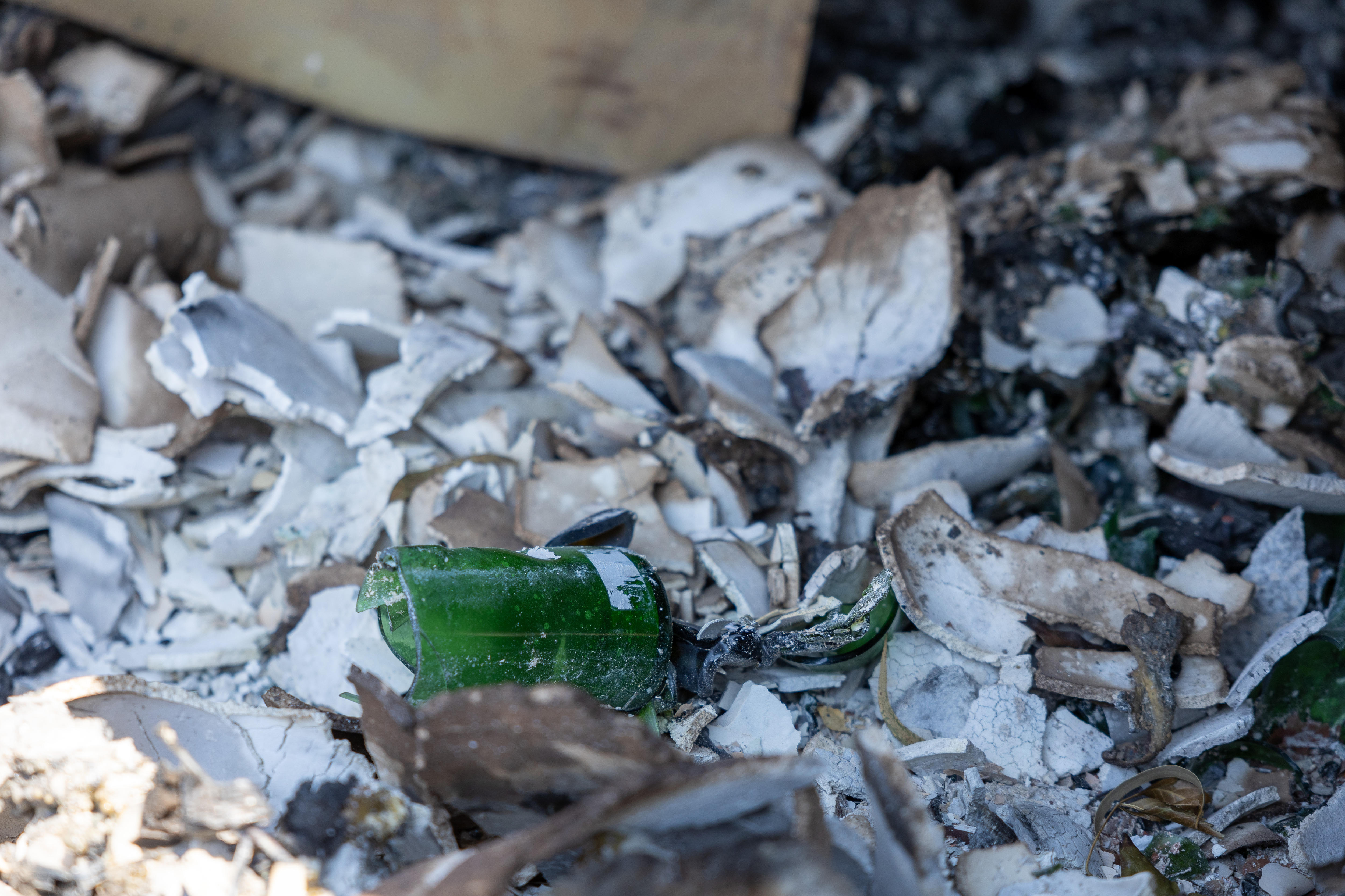 Uma garrafa de vinho queimada está entre os escombros carbonizados.