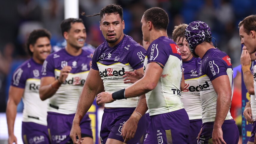 A Melbourne Storm NRL player looks at his teammate as they walk back after scoring a try.