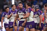 A Melbourne Storm NRL player looks at his teammate as they walk back after scoring a try.