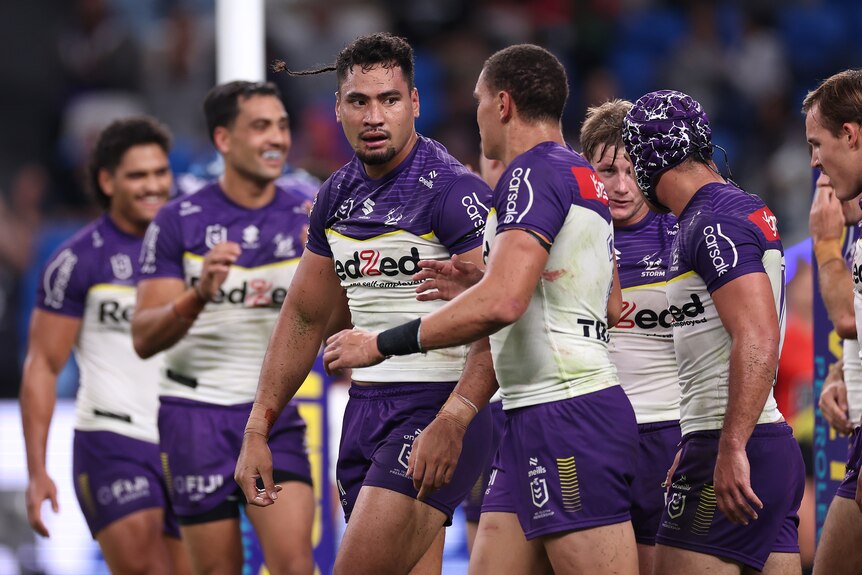 A Melbourne Storm NRL player looks at his teammate as they walk back after scoring a try.