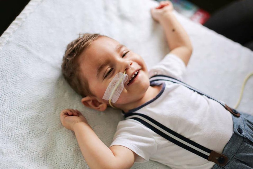 Critically ill 20-month-old Tyler Flaskas lying on a blanket.
