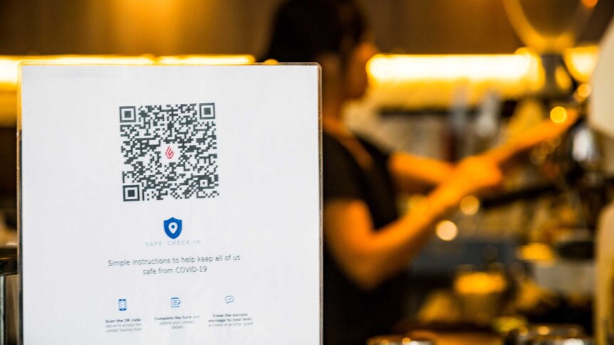 a stand showing off a QR code with a female barista in the background