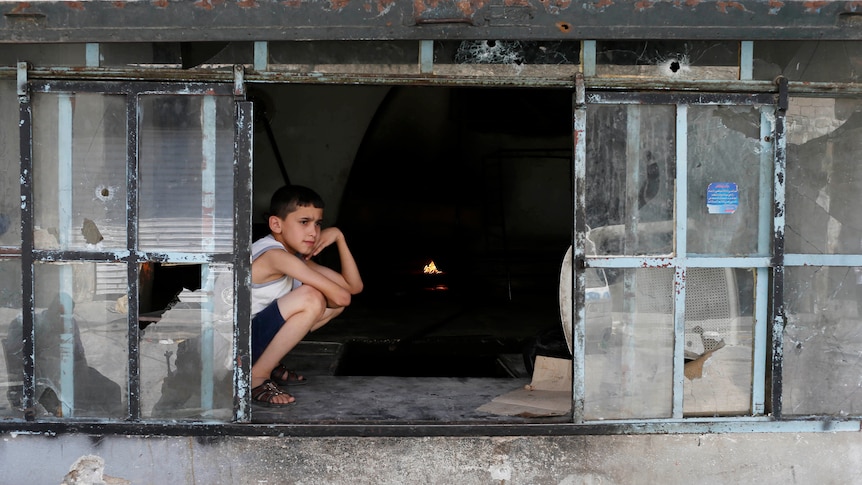 Boy sits at Aleppo bakery