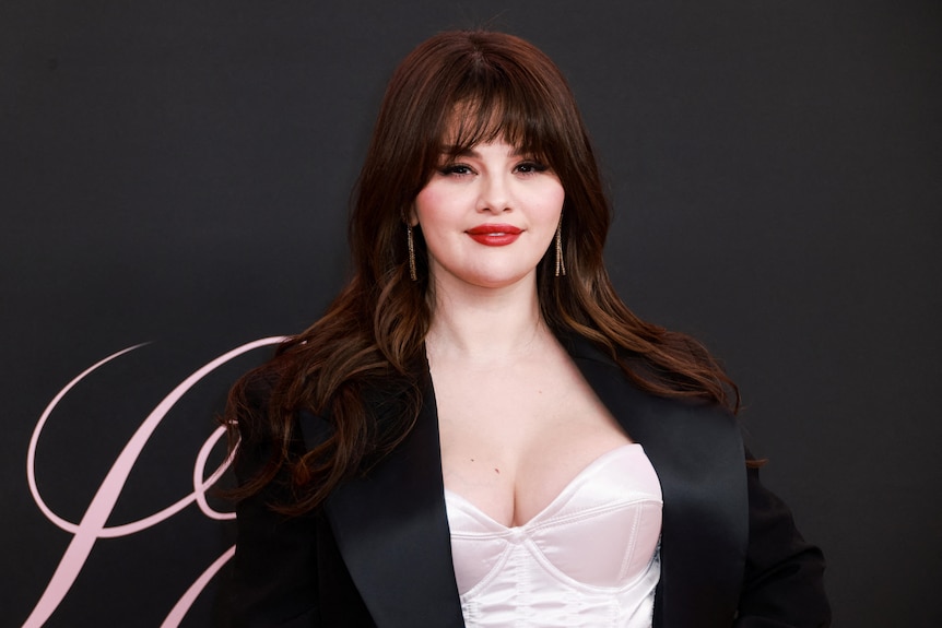 Selena Gomez with a pink bodice and black suit jacket, red lipstick, long dark hair