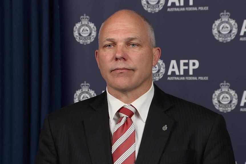 A man in a dark suit and red tie.