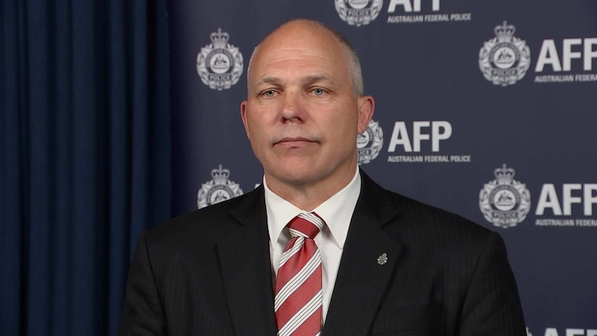 A man in a dark suit and red tie.