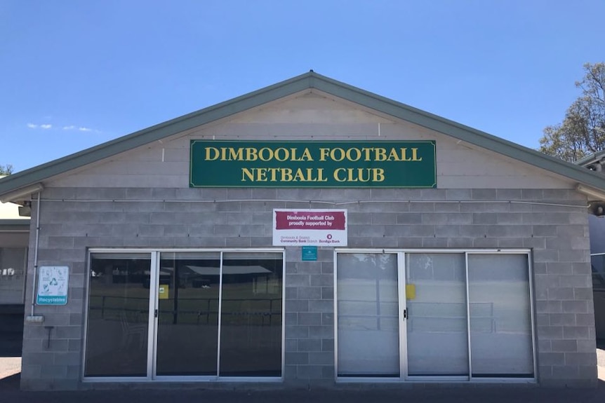 a greay brick building with a blue green sign that read dimbool football netball club