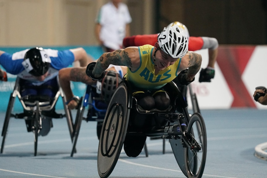 Rheed McCracken racing in a wheelchair. He is wearing an Australian uniform top and a white helmet. He is heavily tattooed.