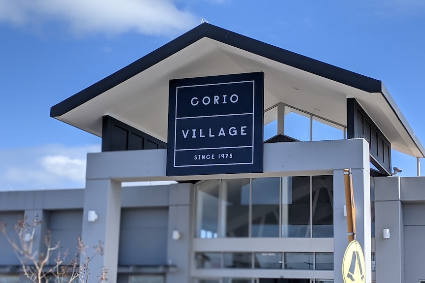 The entrance to Corio Village, viewed from outside, under a blue sunny sky.