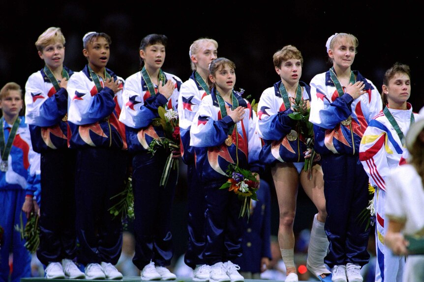 American gymnast Kerri Strug (3R) stands on the medal dais with a hurt ankle in Atlanta.