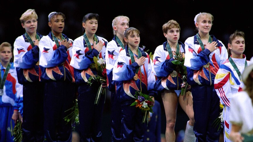 American gymnast Kerri Strug (3R) stands on the medal dais with a hurt ankle in Atlanta.