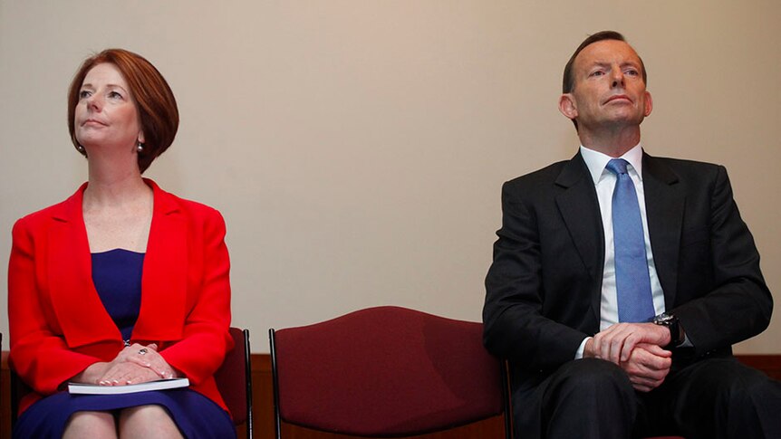 Tony Abbott and Julia Gillard sit next to each other separated by a seat