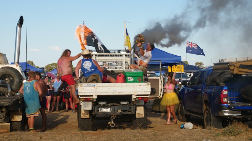 a photo of people on a ute, with flames and smoke coming out of a pipe. Can see australian flags and eskies