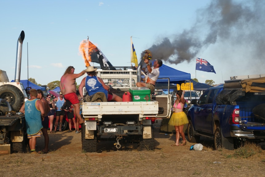 a photo of people on a ute, with flames and smoke coming out of a pipe. Can see australian flags and eskies