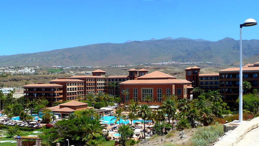 A resort with a pool in front of a mountain.