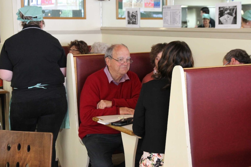 Older people sit in an old-style cafe booth