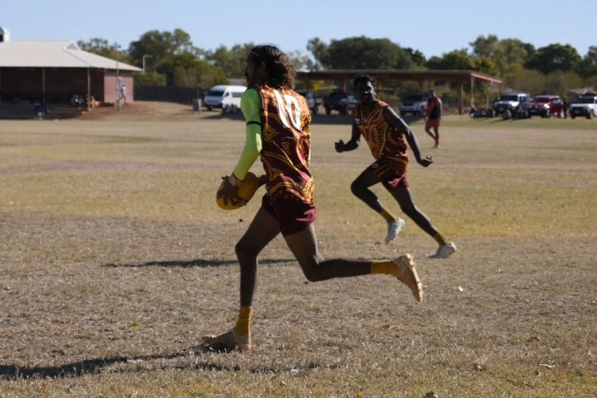 A Halls Creek Hawks player about to kick the football during a match