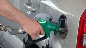 Hand on nozzle of petrol pump bowser.