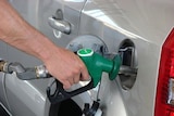 Hand on nozzle of petrol pump bowser.