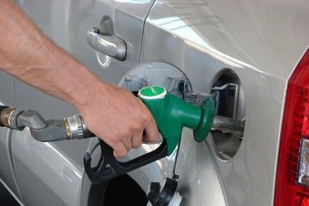 An arm pumps fuel into a car at a petrol station.