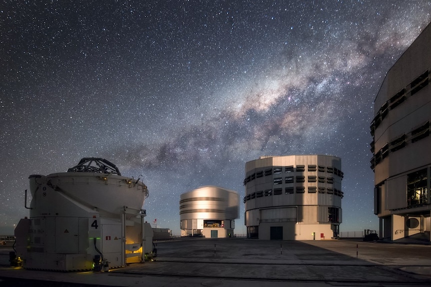 Several squat research buildings in a desert landscape with the milky way in the sky.