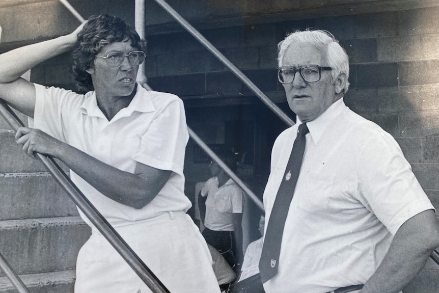 A black and white photo of a man and a woman talking on a set of stairs