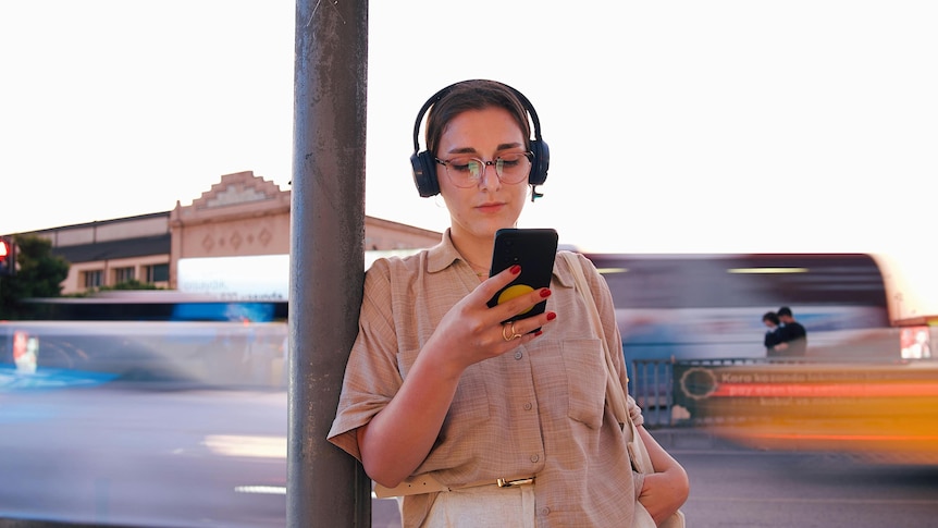 Hipster woman listens to earphones on busy street
