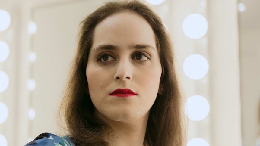 Abby Stein featured in InStyle magazine photo shoot, standing in front of dressing room lights.