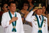 Philippine President Rodrigo Duterte stands to attention next to Armed Forces chief of staff General Eduardo Ano.